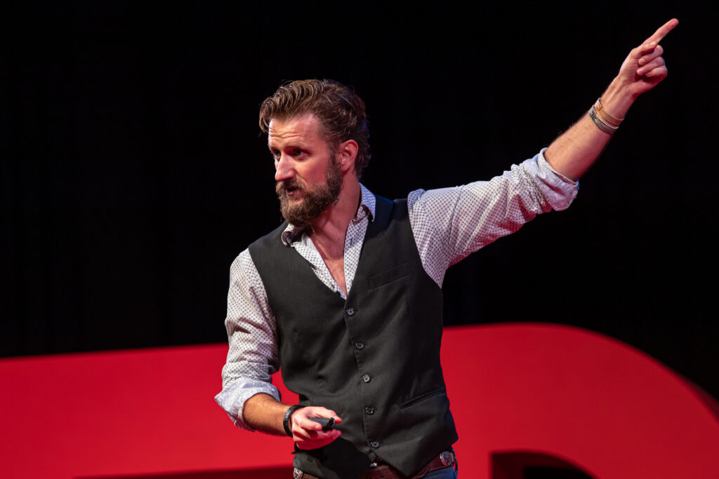 Zachary Moses pointing while speaking on the TEDxOgden stage