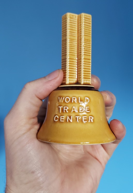 hand holding a bell shaped like the original world trade center towers